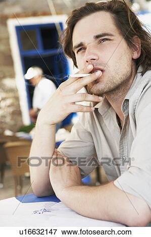 Man smoking cigaret in restaurant View Large Photo Image Stock Photo - Man smoking cigaret in restaurant. Fotosearch