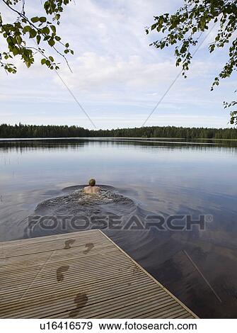 Stock Photo - Man swimming in still lake. Fotosearch