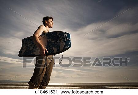 Stock Image - Man with boogie board on beach. Fotosearch
