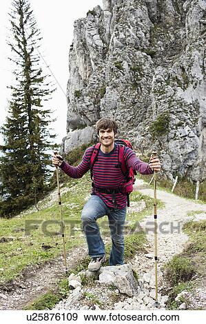 Stock Photo - Man with hiking poles on mountain trail. Fotosearch