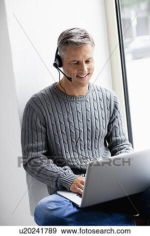 Stock Photo - Man with laptop phoning. Fotosearch