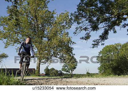 Man with mountain bike under blue skies View Large Photo Image Picture - Man with mountain bike under blue skies. Fotosearch
