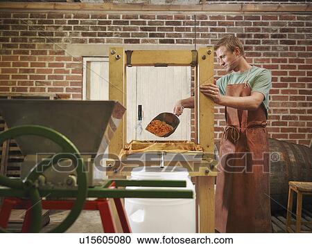 Stock Image - Man with organic cider press. Fotosearch