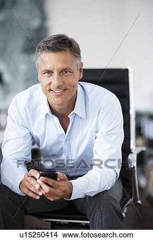 Man with phone sitting in chair View Large Photo Image Picture - Man with phone sitting in chair. Fotosearch
