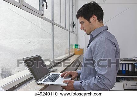 Man working on his laptop View Large Photo Image Stock Image - Man working on his laptop. Fotosearch