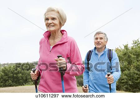 Stock Photo - Mature couple doing nordic walking. Fotosearch
