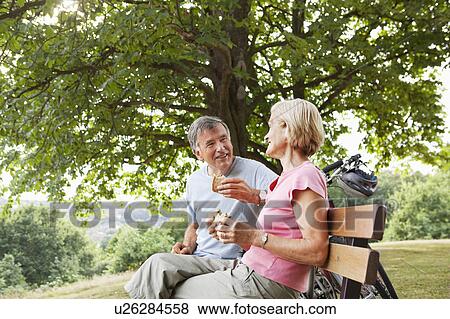 Stock Photo - Mature couple having lunch in park. Fotosearch
