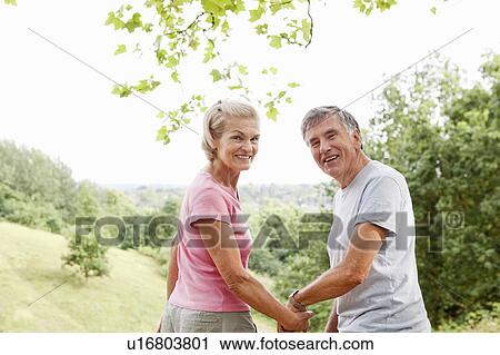 Mature couple holding hands looking back View Large Photo Image Stock Image - Mature couple holding hands looking back. Fotosearch