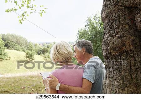 Picture - Mature couple reading book in park. Fotosearch