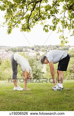Mature couple stretching, touching toes View Large Photo Image Stock Photograph - Mature couple stretching, touching toes. Fotosearch