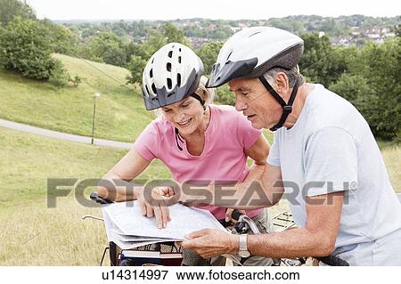 Mature cyclists looking at map in park View Large Photo Image Stock Photo - Mature cyclists looking at map in park. Fotosearch