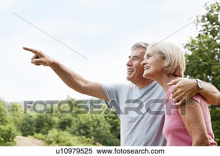 Stock Photography - Mature man embracing woman points away. Fotosearch