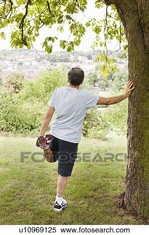 Mature man stretches leg in park View Large Photo Image Stock Photography - Mature man stretches leg in park. Fotosearch
