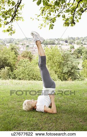 Mature woman doing headstand in park View Large Photo Image Stock Image - Mature woman doing headstand in park. Fotosearch