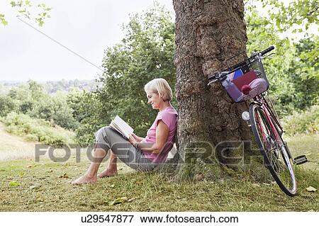 Stock Photo - Mature woman reading book in park. Fotosearch