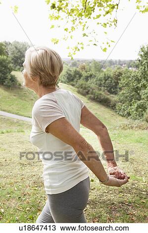 Mature woman stretches arms behind back View Large Photo Image Stock Image - Mature woman stretches arms behind back. Fotosearch