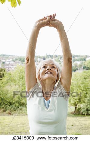Mature woman stretches arms out View Large Photo Image Stock Photo - Mature woman stretches arms out. Fotosearch