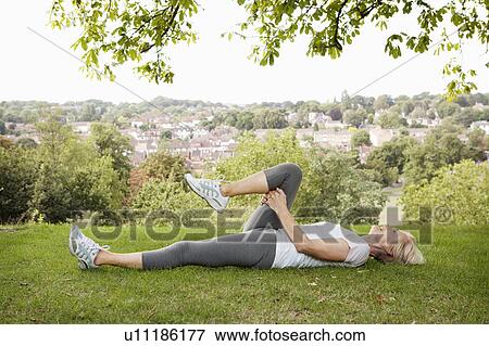 Mature woman stretches leg in park View Large Photo Image Stock Photo - Mature woman stretches leg in park. Fotosearch
