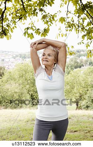 Stock Image - Mature woman stretching arms above head. Fotosearch