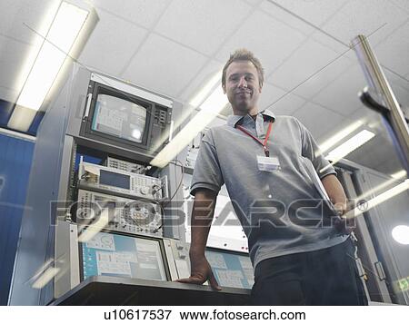 Stock Photo - Men works at satellite dish control desk. Fotosearch