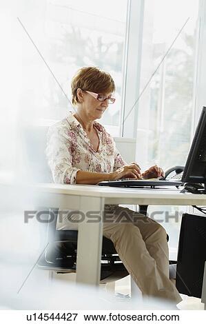 Middle-aged woman working at computer View Large Photo Image Stock Photo - Middle-aged woman working at computer. Fotosearch