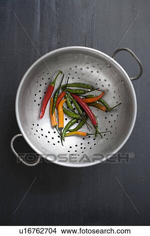Picture - Mixed color chilies on colander. Fotosearch