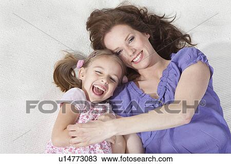 Stock Image - Mother and daughter on rug having fun. Fotosearch