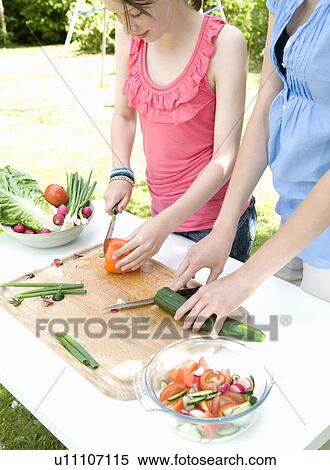 Stock Photography - Mother and daughter prepare salad in gdn. Fotosearch