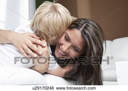 Mother hugging son on couch at home View Large Photo Image Stock Photo - Mother hugging son on couch at home. Fotosearch