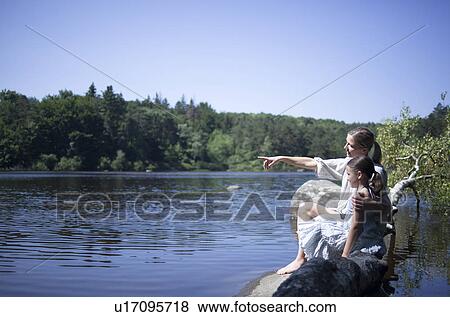 Mum and daughter sitting by a lake View Large Photo Image Stock Photo - Mum and daughter sitting by a lake. Fotosearch