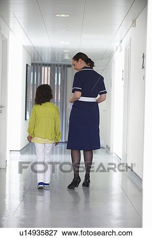 Stock Photo - Nurse and young girl walking in corridor. Fotosearch