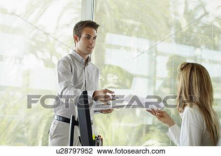 Office worker handing document to woman View Large Photo Image Stock Image - Office worker handing document to woman. Fotosearch