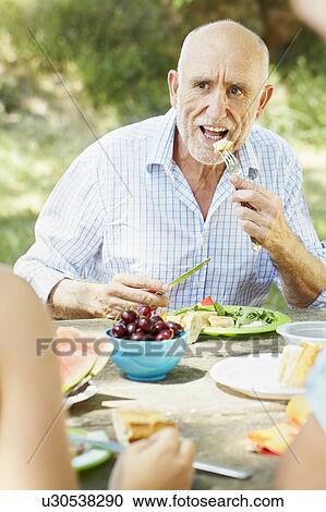 Older man eating at picnic table View Large Photo Image Stock Image - Older man eating at picnic table. Fotosearch