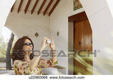Stock Photo - Older tourist woman taking a snapshot. Fotosearch