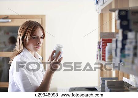Pharmacist looking at bottle of pills View Large Photo Image Stock Photo - Pharmacist looking at bottle of pills. Fotosearch
