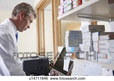 Pharmacist looking at computer View Large Photo Image Stock Photograph - Pharmacist looking at computer. Fotosearch