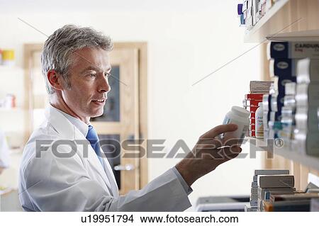 Picture - Pharmacist looking at pill bottle. Fotosearch