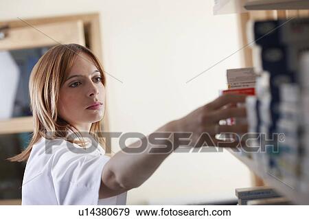 Stock Photo - Pharmacist looking at pill bottle. Fotosearch