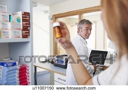 Pharmacist looking at pills in bottle View Large Photo Image Stock Image - Pharmacist looking at pills in bottle. Fotosearch