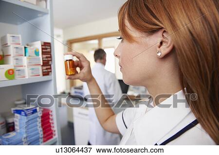 Pharmacist looking at pills in bottle View Large Photo Image Stock Photo - Pharmacist looking at pills in bottle. Fotosearch