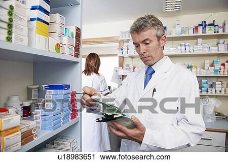 Pharmacist looking at prescription View Large Photo Image Stock Image - Pharmacist looking at prescription. Fotosearch