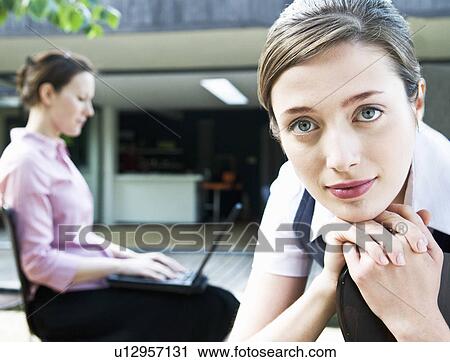 Stock Image - Portrait of business woman + colleague. Fotosearch