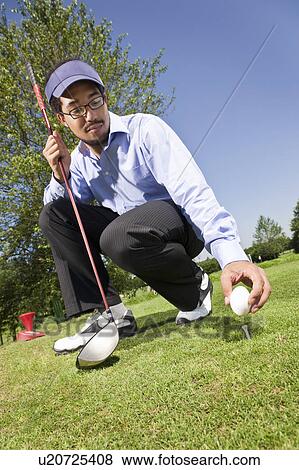 Stock Photo - Putting an egg on the tee. Fotosearch