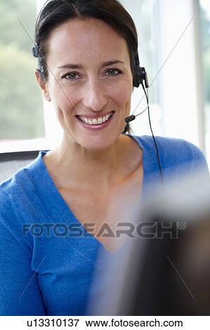 Stock Photo - Receptionist behind her desk, smiling. Fotosearch