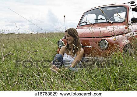 Stock Photo - Relaxed female by car in countryside. Fotosearch