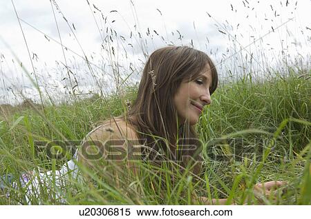 Relaxed female lying in long grass View Large Photo Image Stock Photography - Relaxed female lying in long grass. Fotosearch