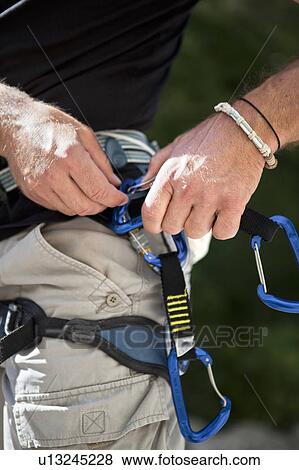 Stock Photo - Rock climber checking equipment. Fotosearch