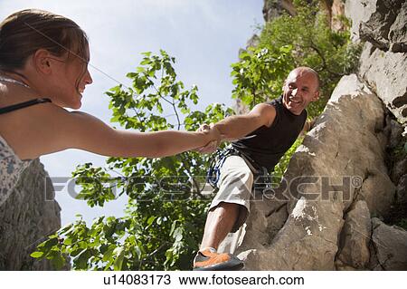 Rock climber helping partner View Large Photo Image Stock Image - Rock climber helping partner. Fotosearch