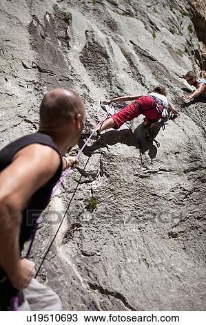 Stock Image - Rock climber securing partner. Fotosearch
