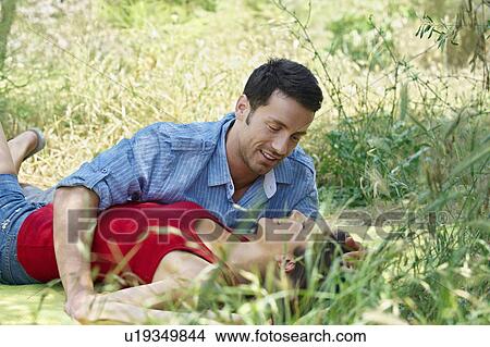 Picture - Romantic couple lying in long grass. Fotosearch